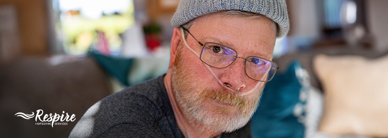 Man in a winter hat with oxygen tubes in his nose